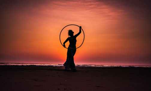 silhouette boy on beach against sky during sunset